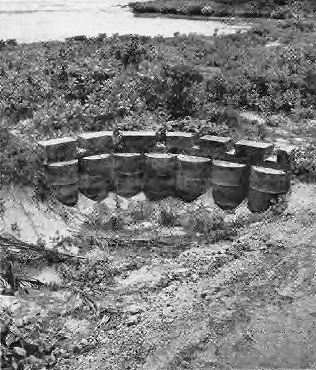 CONCRETE GUN CRENELLATION RESTS ON DRUMS IN ROADSIDE POSITION.